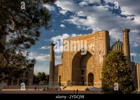 Samarkand, Usbekistan - 5. Juli 2024: Fassade von Sher-Dor Madrasah auf dem Registan-Platz in Samarkand mit Touristen bei Sonnenuntergang Stockfoto