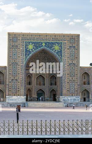 Samarkand, Usbekistan - 5. Juli 2024: Portal und Säulen in Ulug betteln Madrassa in der Registan von Samarkand mit Blumengarten bei Sonnenuntergang Stockfoto