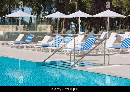 Sonnenliegen und Sonnenschirme am Pool an einem sonnigen Tag Stockfoto
