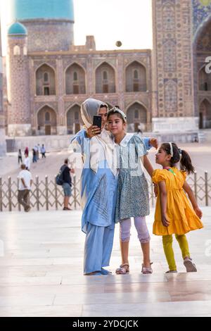 Samarkand, Usbekistan – 5. Juli 2024: Muslimische Mutter mit Kopftuch macht ein Selfie mit ihren Töchtern auf dem Registan-Platz in Samarkand Stockfoto