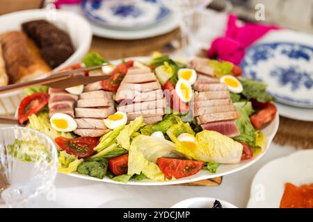 Eine Nahaufnahme eines Tellers mit einem köstlichen Nicoise-Salat. Duftende Thunfischscheiben mit Wachteleiern und Gemüse. Französisches Gericht mit frischem Kohl, Tomaten Stockfoto