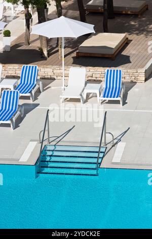 Sonnenliegen und Sonnenschirme am Pool an einem sonnigen Tag Stockfoto