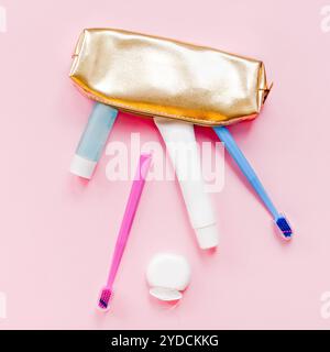 Zähne, Hygiene und mündlichen Zahnpflege Produkte in goldenen Travel cosmetic Geldbeutel kit Pastell rosa Farbe Hintergrund mit kopieren. Leere Tube Zahnpasta Stockfoto