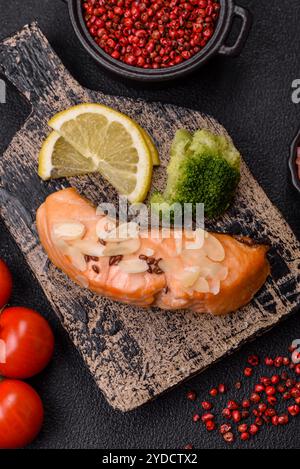 Ein Stück gekochter Lachs mit Reis, Brokkoli, Salz und Gewürzen auf dunklem Betonhintergrund Stockfoto