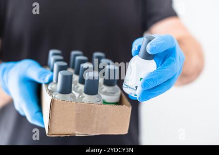 Handdesinfektionsmittel Hygiene Alkohol Gel Flaschen in den Händen des Mannes trägt Latex medizinische Handschuhe und Schutzmaske während Coronavirus COVID-19 Pandemien. Hea Stockfoto