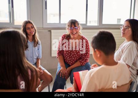 Glückliche Jugendlehrerin während eines dynamischen Philosophiekurses im Kreis mit ihren Schülern. Stockfoto