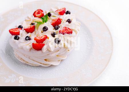 Pavlova-Kuchen mit Sahne und frischen Beeren auf Teller Stockfoto