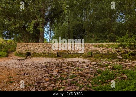 Trockenmauer, die die Themse nahe der Quelle überquert. Stockfoto