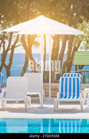 Sonnenliegen und Sonnenschirme am Pool an einem sonnigen Tag Stockfoto