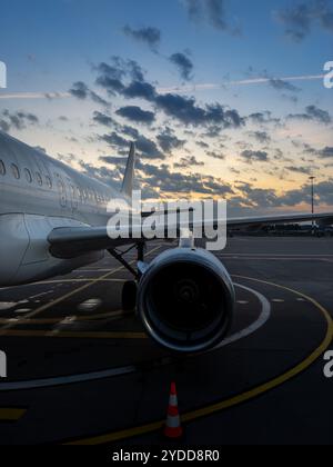 Das Flugzeug parkte während des Sonnenuntergangs auf dem Tarmac mit bunten Wolken im Hintergrund an einem Flughafen Stockfoto