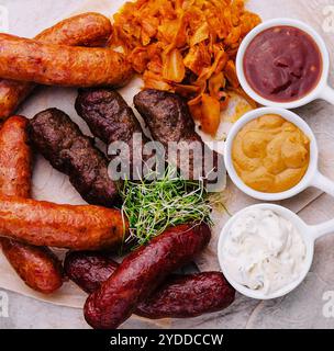 Bierset mit gegrillten Würstchen mit gedünstetem Kohl und Saucen Stockfoto