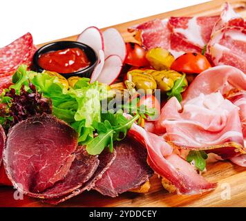 Verschiedene Fleischsorten, Würstchen, Salami, Schinken, Oliven, auf einem Holzbrett Stockfoto