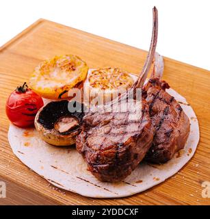 Gegrillte Lammkoteletts auf Holzbrett mit Kräutern und Gewürzen Stockfoto