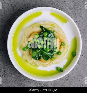 Kartoffelpüree mit Butter, grünen Erbsen, Basilikum in einer weißen Schüssel Stockfoto