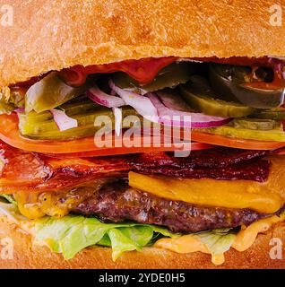 Burger mit Rindfleisch, Tomaten, Käse, Speck und Salat Makro Stockfoto