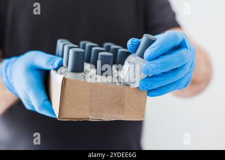 Handdesinfektionsmittel Hygiene Alkohol Gel Flaschen in den Händen des Mannes trägt Latex medizinische Handschuhe und Schutzmaske während Coronavirus COVID-19 Pandemien. Hea Stockfoto