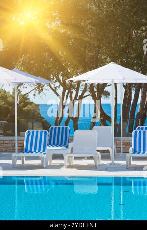 Sonnenliegen und Sonnenschirme am Pool an einem sonnigen Tag Stockfoto