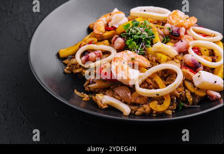 Thailändischer, scharfer Salat mit Meeresfrüchten auf schwarzem Teller Stockfoto