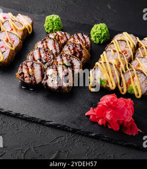 Set gebackene Sushi-Brötchen mit Wasabi und Ingwer auf Schwarz Stockfoto