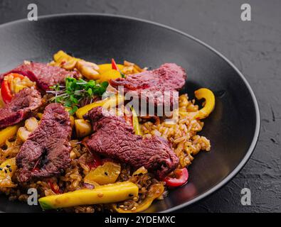 Chinesischer gebratener Reis mit Rindfleisch auf schwarzem Teller Stockfoto