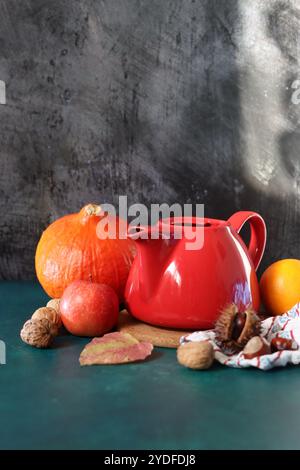 Rote dampfende Teekanne aus der Nähe. Heißer Tee in einem Topf und hausgemachte Kekse auf einem Tisch. Dunkler Hintergrund mit Kopierraum. Warmer Winterabend Stockfoto