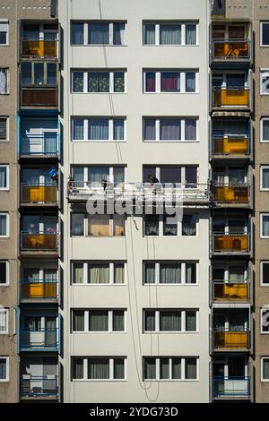 Budapest, Ungarn – Arbeiter, die auf einer Hängeplattform stehen, malen und renovieren ein altes zehnstöckiges Wohnpaneelgebäude in Budapest Stockfoto