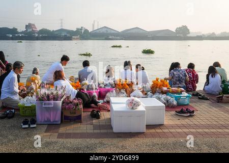 Ein Blick auf die Menschen, die sich am Ufer des Chao Phraya River versammeln, während sie auf die Mönche warten, um Almosen bei den Booten zu sammeln, im Wat Chin Wararam Worawihan Tempel in der Provinz Pathum Thani, Thailand. Die Tradition, hundert Mönchen in Pathum Thani, Thailand, Almosen zu geben, ist eine jahrhundertealte buddhistische Zeremonie, die entlang von Flüssen und Kanälen nach dem Ende der buddhistischen Fastenzeit stattfindet. Mönche versammeln sich in Booten, um Opfer von Einheimischen zu erhalten, die Essen zubereiten und an der Verdienste teilnehmen. Diese Veranstaltung feiert Gemeinschaft, Glauben und kulturelles Erbe. Stockfoto