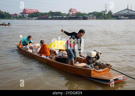 Thailand. Oktober 2024. Ein Ruderbootfahrer wird beobachtet, wie er den Motor des Bootes startet, während ein Mönch im Inneren sitzt, umgeben von den Angeboten der Menschen auf dem Chao Phraya River. Die Tradition, hundert Mönchen in Pathum Thani, Thailand, Almosen zu geben, ist eine jahrhundertealte buddhistische Zeremonie, die entlang von Flüssen und Kanälen nach dem Ende der buddhistischen Fastenzeit stattfindet. Mönche versammeln sich in Booten, um Opfer von Einheimischen zu erhalten, die Essen zubereiten und an der Verdienste teilnehmen. Diese Veranstaltung feiert Gemeinschaft, Glauben und kulturelles Erbe. Quelle: SOPA Images Limited/Alamy Live News Stockfoto