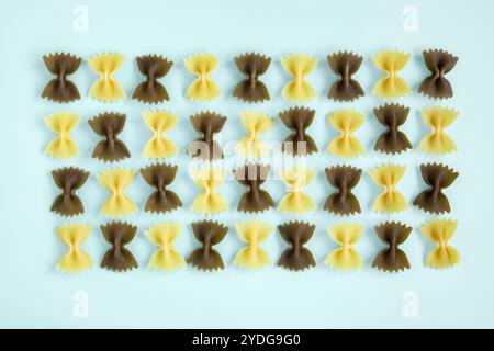 Pasta mit Schleife in Reihen auf pastellblauem Hintergrund angeordnet Stockfoto