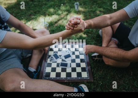 Freunde Armwrestling in einem Park neben einem Schachbrett Stockfoto