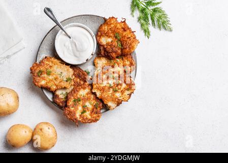 Kartoffellatkes mit Kräutern und Sahnesauce auf weißem Hintergrund, Draufsicht, Kopierraum. Traditionelle jüdische Latkes oder Levivot. Stockfoto