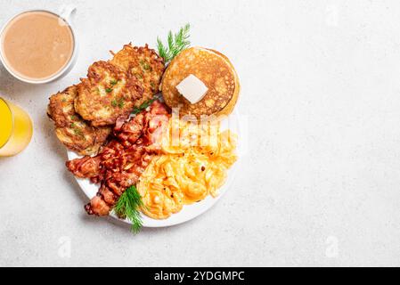 Hausgemachtes komplettes amerikanisches Frühstück mit Rührei, Speck, Kartoffelrösti und Pfannkuchen, Butter, Kaffee und Saft auf weißem Hintergrund, Blick von oben, Kopie sp Stockfoto