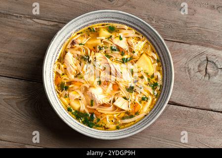 Hausgemachte Chicken Nudelsuppe auf hölzernem Hintergrund, Blick von oben. Schüssel mit heißer Hühnersuppe, gesundes Komfortessen. Stockfoto