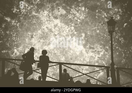 Silhouetten von Menschen auf der Brücke bei Sonnenuntergang in Paris (Frankreich). Retro-Foto mit Kratzern. Stockfoto