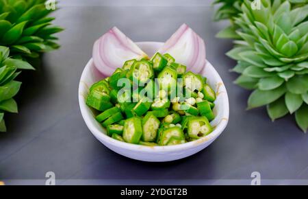 Frisches Gemüse Zwiebeldame Finger in einer weißen Keule. Indisches vegetarisches Food-Konzept mit Okra-Ladies-Finger und gehackter Zwiebelscheibe. Stockfoto