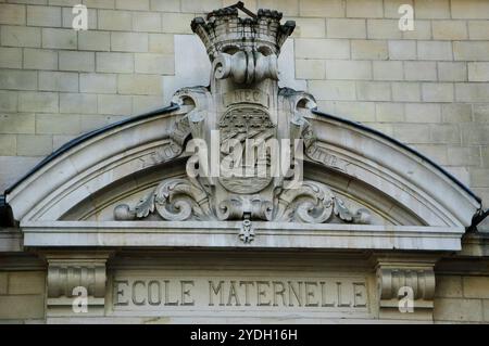 Pariser Kindergarten ('ecole maternelle' auf französisch), Außenfassade mit Stadtwappen. Paris, Frankreich. Stockfoto