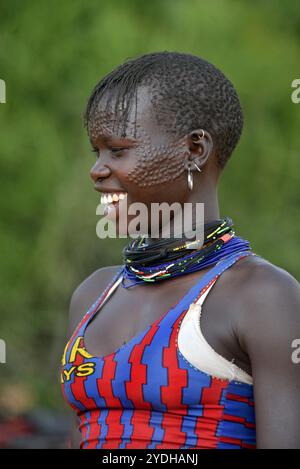 Ein lächelndes Karimojong-Mädchen mit Gesichtstätowierungen in Kotido, Karamoja Uganda. Unter den Karimojong-Stämmen symbolisieren die Gesichtstattoos Schönheit. Stockfoto