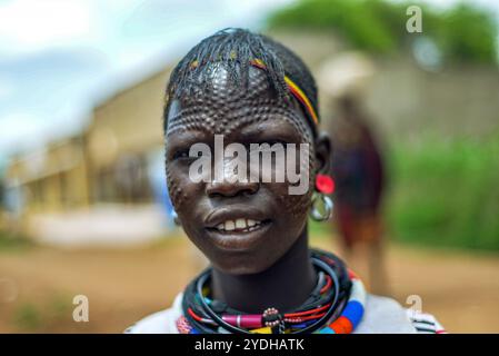 Ein lächelndes Karimojong-Mädchen mit Gesichtstätowierungen in Kotido, Karamoja Uganda. Unter den Karimojong-Stämmen symbolisieren die Gesichtstattoos Schönheit. Stockfoto