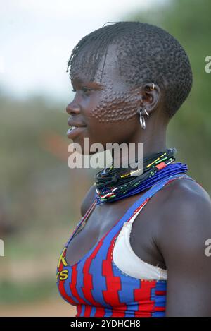 Ein lächelndes Karimojong-Mädchen mit Gesichtstätowierungen in Kotido, Karamoja Uganda. Unter den Karimojong-Stämmen symbolisieren die Gesichtstattoos Schönheit. Stockfoto