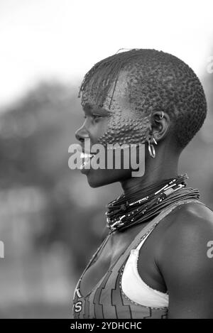 Ein lächelndes Karimojong-Mädchen mit Gesichtstätowierungen in Kotido, Karamoja Uganda. Unter den Karimojong-Stämmen symbolisieren die Gesichtstattoos Schönheit. Stockfoto