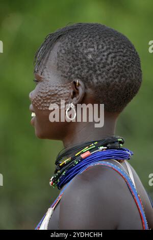 Ein lächelndes Karimojong-Mädchen mit Gesichtstätowierungen in Kotido, Karamoja Uganda. Unter den Karimojong-Stämmen symbolisieren die Gesichtstattoos Schönheit. Stockfoto