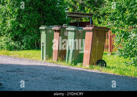 Vier Mülltonnen stehen an einem sonnigen Sommertag darauf, von den Sanitärangehörigen geleert zu werden. Die Behälter bestehen aus Kunststoff und sind unterschiedlich Stockfoto