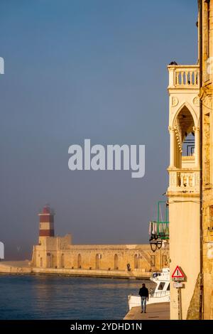 Blick auf den Palazzo Martinelli Meo Evoli und den roten Leuchtturm in Porto Vecchio, Monopoli, Italien, an einem nebeligen Tag. Stockfoto