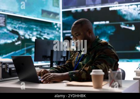Der Geheimdienstmitarbeiter in einem erweiterten Kontrollraum übernimmt die Überwachung und interpretiert Echtzeitdaten für Sicherheitsmaßnahmen zum Schutz nationaler Interessen. Spezialist für Betriebsbasis. Stockfoto