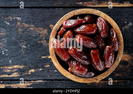 Getrocknete Datteln in Holzschale auf rustikalem Holztisch, Ramadan und gesundes Snack, Top View, Kopierraum Stockfoto