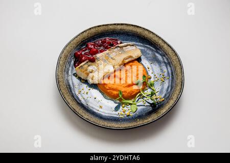 Gebackenes Fischfilet mit süßen Kartoffelpüree und Beerensauce, serviert mit Mikrogrün-Beilage Stockfoto