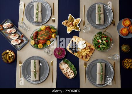 Festliche Gerichte mit gebratenem Huhn als Hauptgericht und Tellern mit Servietten, die mit winzigen Tannenzweigen verziert sind, werden auf dem weihnachtstisch serviert Stockfoto