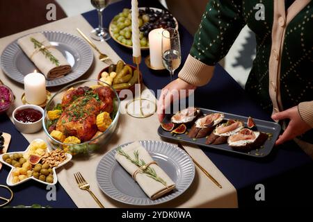 Hochwinkelaufnahme einer nicht erkennbaren Frau Servierteller mit Fleischtartine auf festlichem Esstisch mit gebratenem truthahn am Heiligabend, Kopierraum Stockfoto