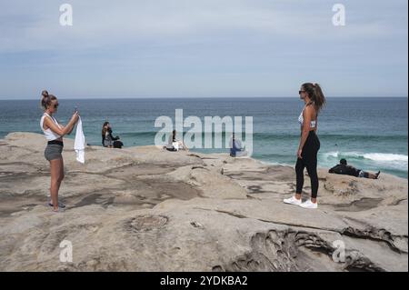 27.09.2019, Sydney, New South Wales, Australien, Eine junge Frau fotografiert ihre Freundin auf den Klippen am Tamarama Point. Touristen schauen nach, um zu sehen Stockfoto