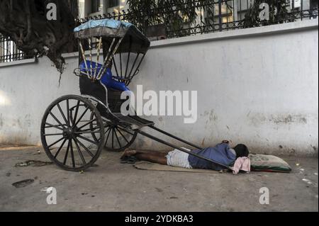 25.02.2011, Kalkutta, Westbengalen, Indien, Asien, ein Rikscha-Fahrer schläft neben seiner hölzernen Rikscha an einem Straßenrand in Kalkutta, der einzigen Stadt Indiens Stockfoto